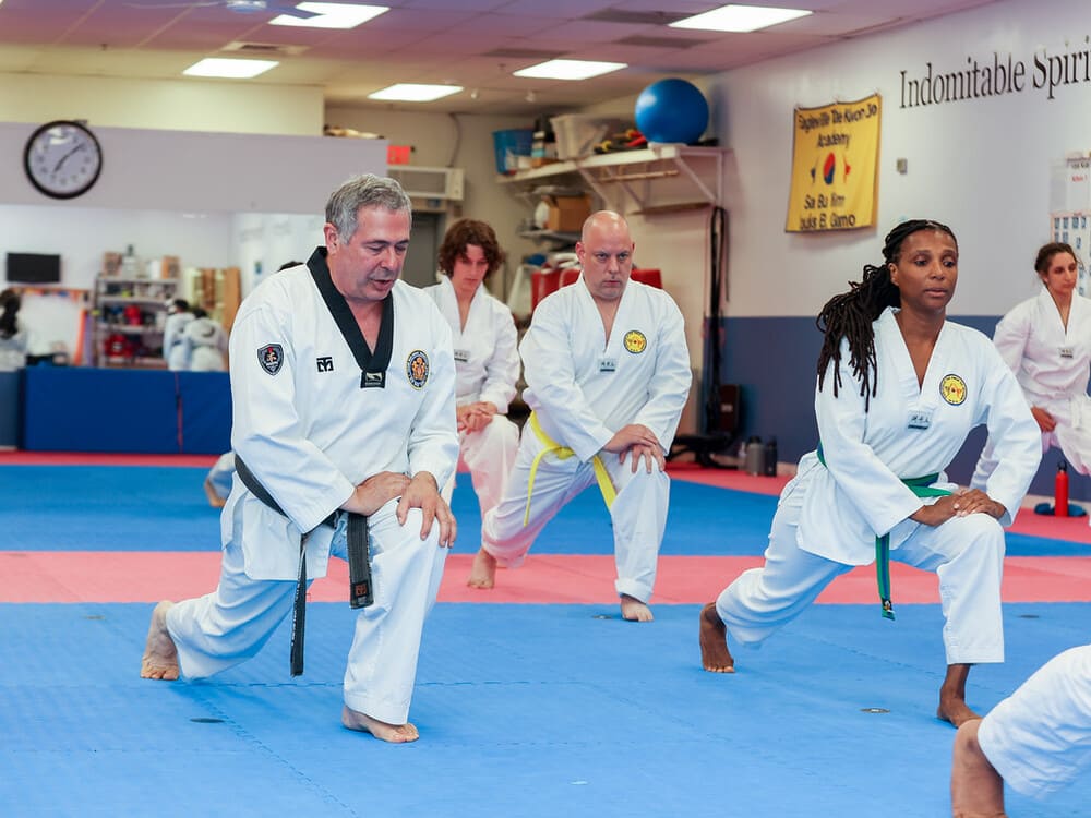 taekwondo instructor showing a group of people on how to warm up or stretching during taekwondo class