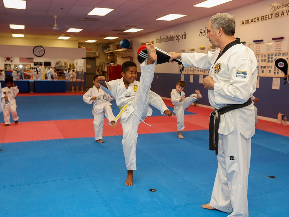 a group of kids practice taekwondo kicking with their master in Norristown PA